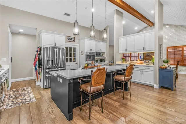 a kitchen with stainless steel appliances kitchen island granite countertop a table chairs cabinets and wooden floor