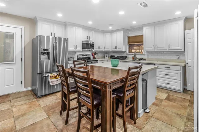 a kitchen with stainless steel appliances a table chairs refrigerator and microwave