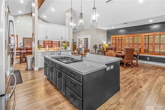 a kitchen with stainless steel appliances granite countertop a stove oven a dining table and chairs with wooden floor