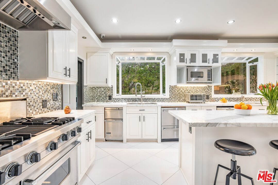 607 North Hillcrest Road Beverly Hills, CA 90210 - Photo 6 of 16 a kitchen with a stove a sink and a refrigerator