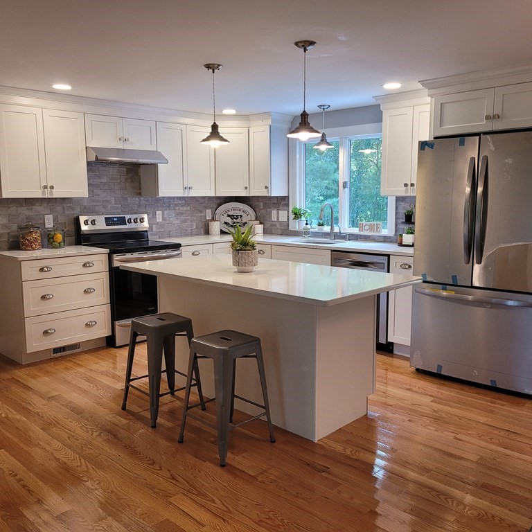 54 Summer Street North Andover, MA 01845 - Photo 6 of 25 a kitchen with stainless steel appliances granite countertop a sink a stove a refrigerator and island with wooden floor