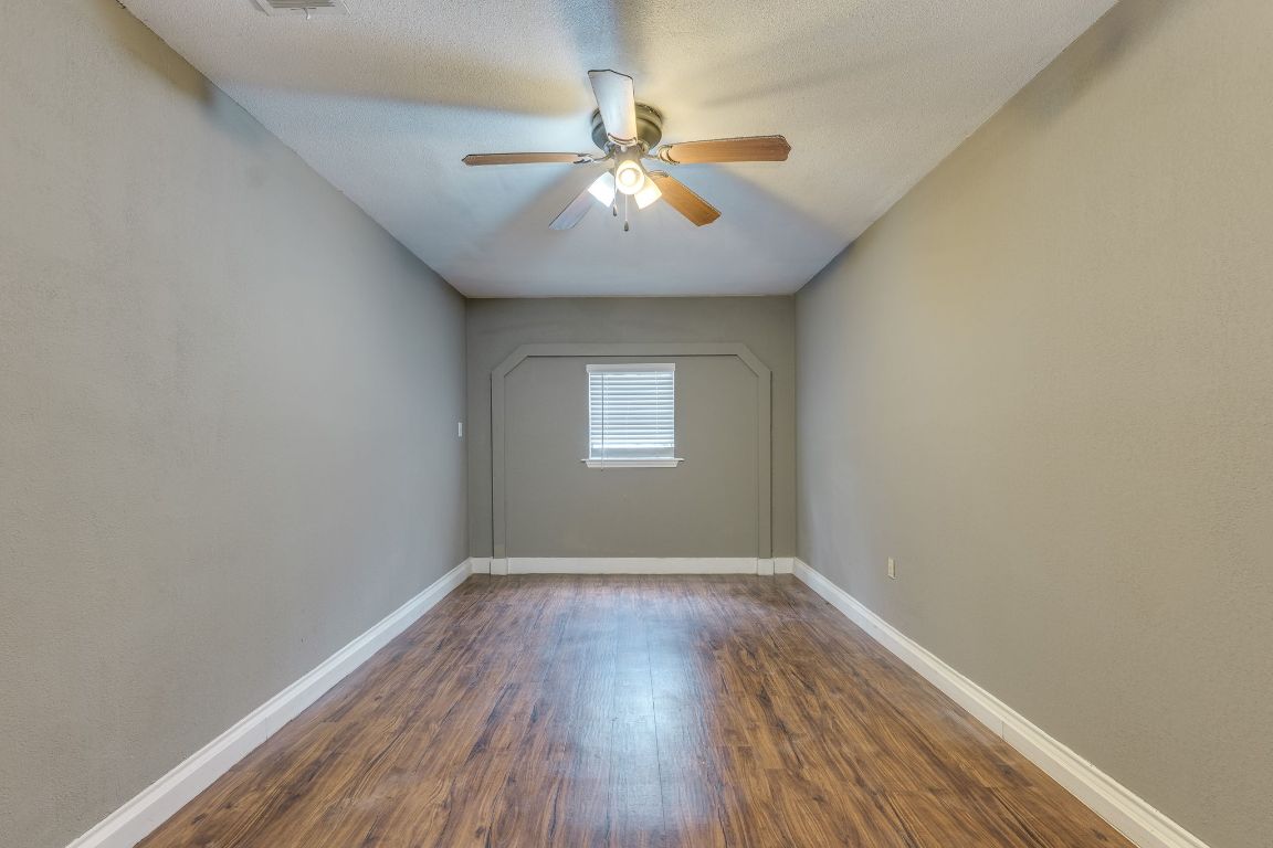 16041 Stoneham Circle Pflugerville, TX 78660 - Photo 20 of 34 an empty room with wooden floor chandelier fan and windows