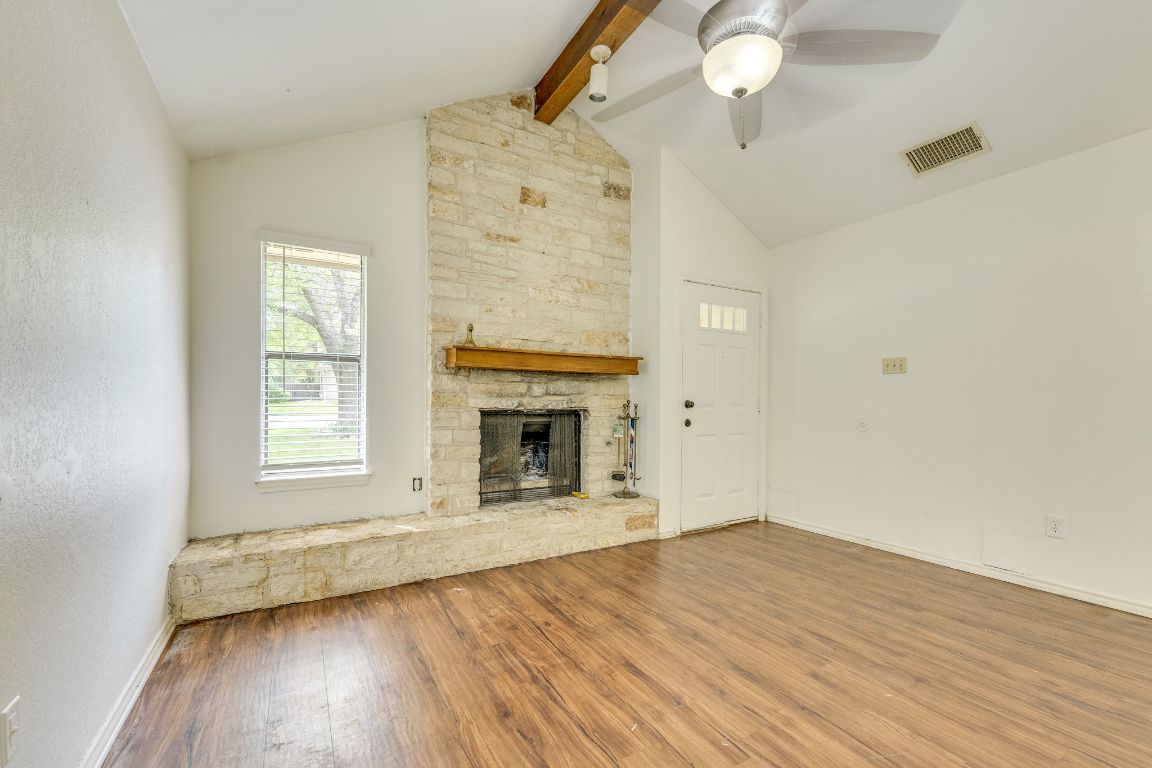 16041 Stoneham Circle Pflugerville, TX 78660 - Photo 6 of 34 an empty room with wooden floor fan and windows