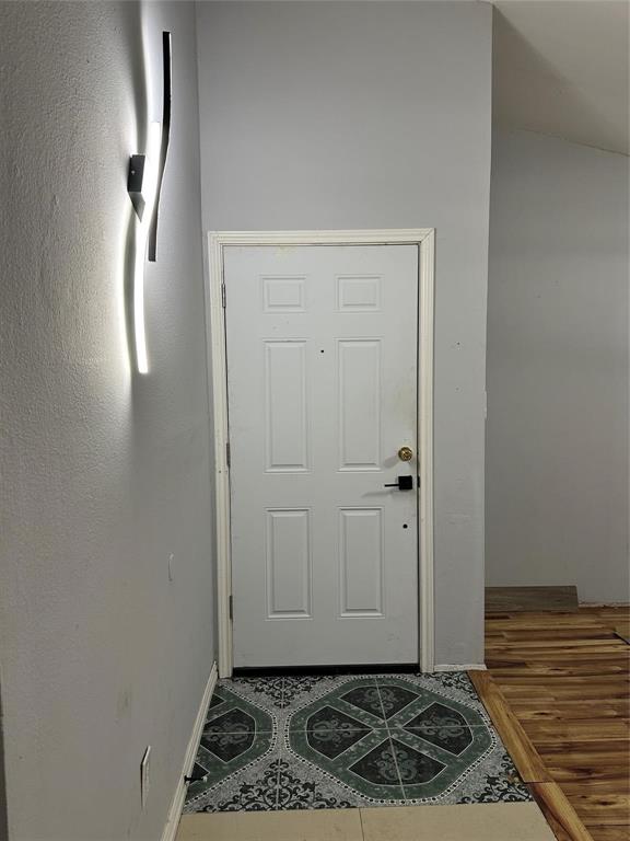 4601 Elm Ridge Lane Garland, TX 75044 - Photo 8 of 21 Six-panel door with matte black hardware, geometric tile flooring, and a modern wall-mounted light fixture