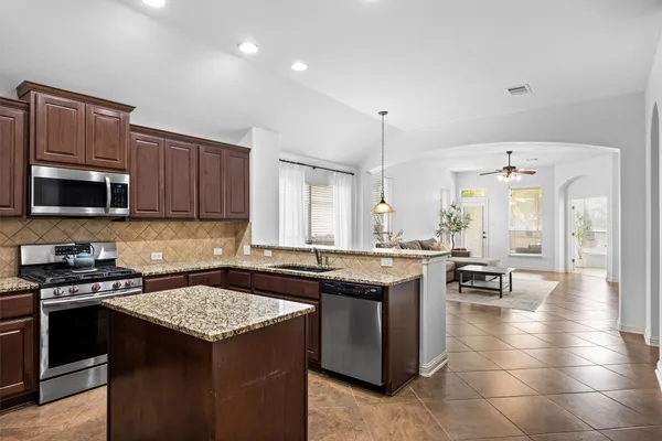 a kitchen with stainless steel appliances granite countertop a stove top oven a refrigerator and a sink