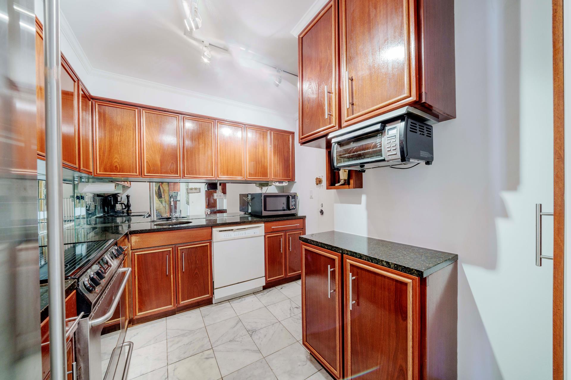 475 Park Avenue, Unit 11BC Manhattan, NY 10022 - Photo 5 of 15 a kitchen with stainless steel appliances granite countertop a sink and cabinets