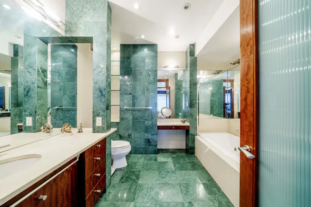 a bathroom with a double vanity sink toilet and tub