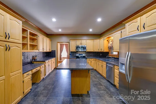 a kitchen with stainless steel appliances granite countertop a refrigerator a stove and a sink