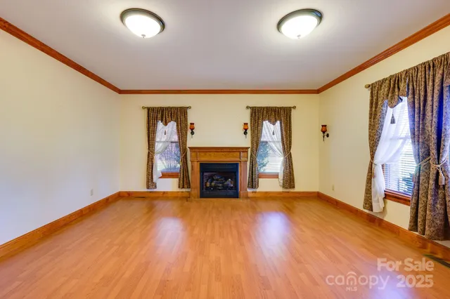 an empty room with wooden floor fireplace and a window