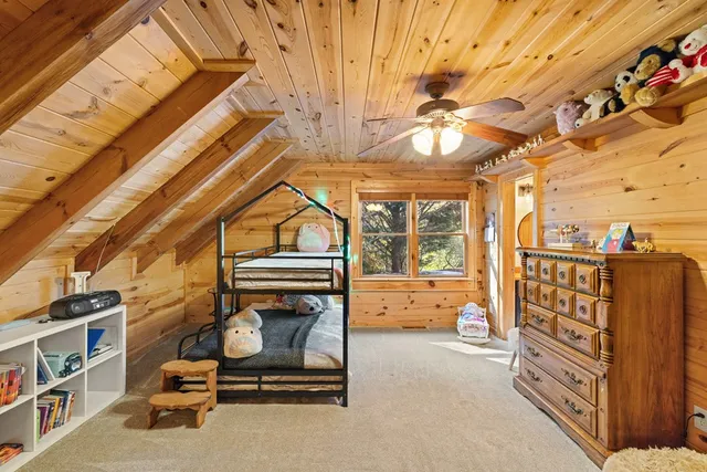 a bedroom with a bed a dresser and next to a window