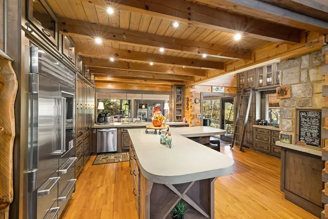 a room with stainless steel appliances kitchen island granite countertop a sink and cabinets
