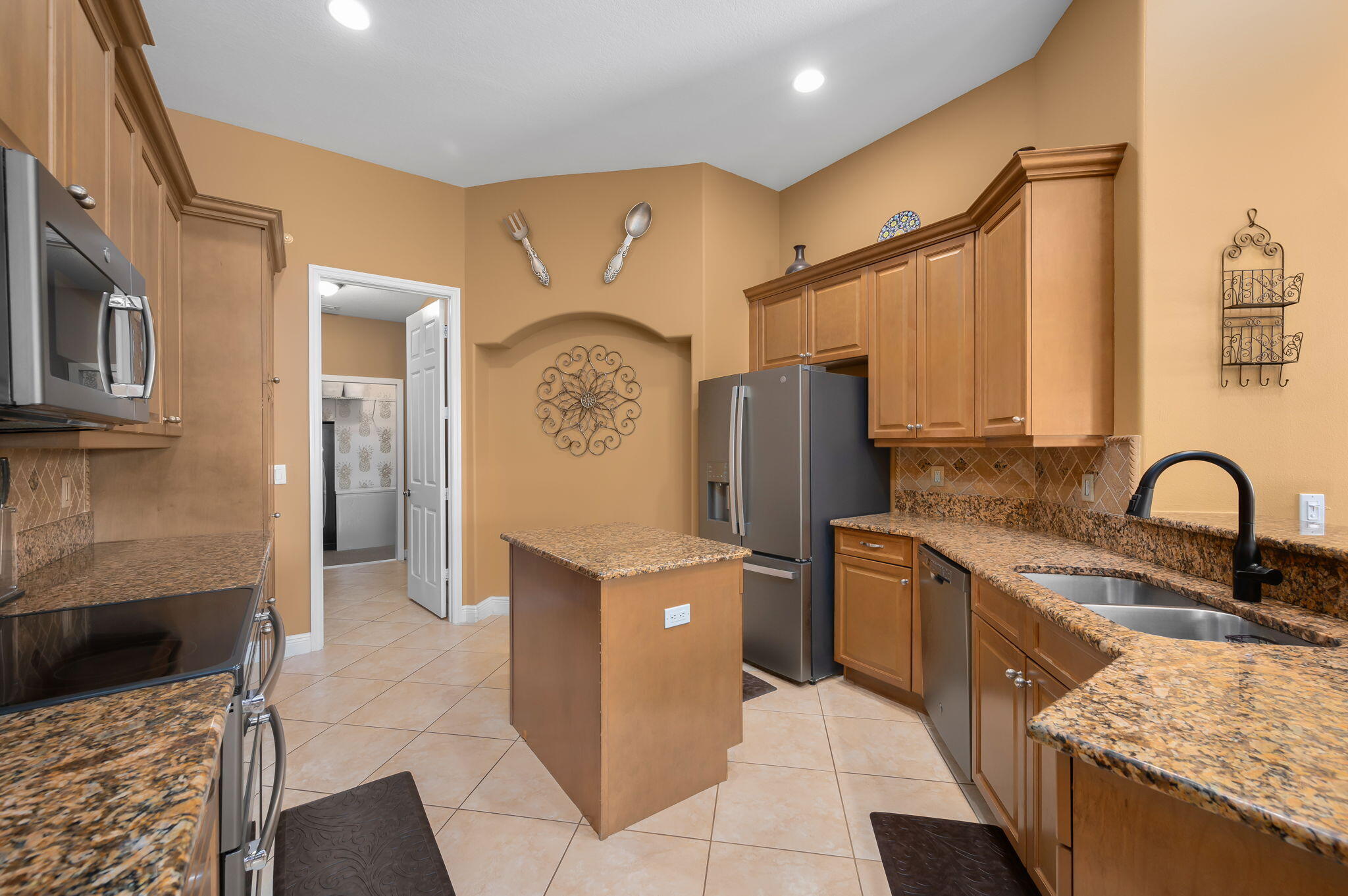 1438 Southwest Apache Avenue Port St. Lucie, FL 34953 - Photo 9 of 34 a kitchen with stainless steel appliances granite countertop a refrigerator and a stove top oven