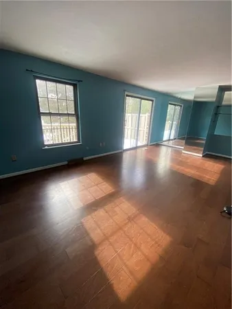 a view of an empty room with window and wooden floor