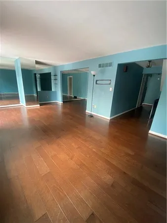 a view of empty room with wooden floor and fan