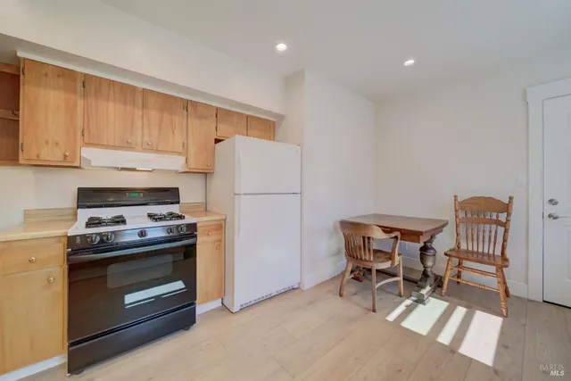 a kitchen with a stove a refrigerator and wooden floor