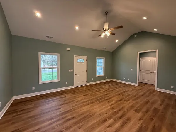 a view of an empty room with window and wooden floor
