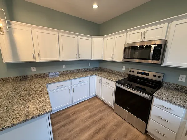 a kitchen with granite countertop a stove microwave and sink