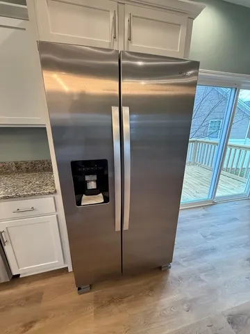 a view of a refrigerator in kitchen and an empty room