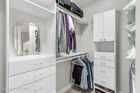 a view of walk in closet with clothes and shoes
