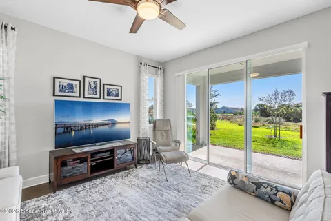 a living room with furniture flat screen tv and a floor to ceiling window