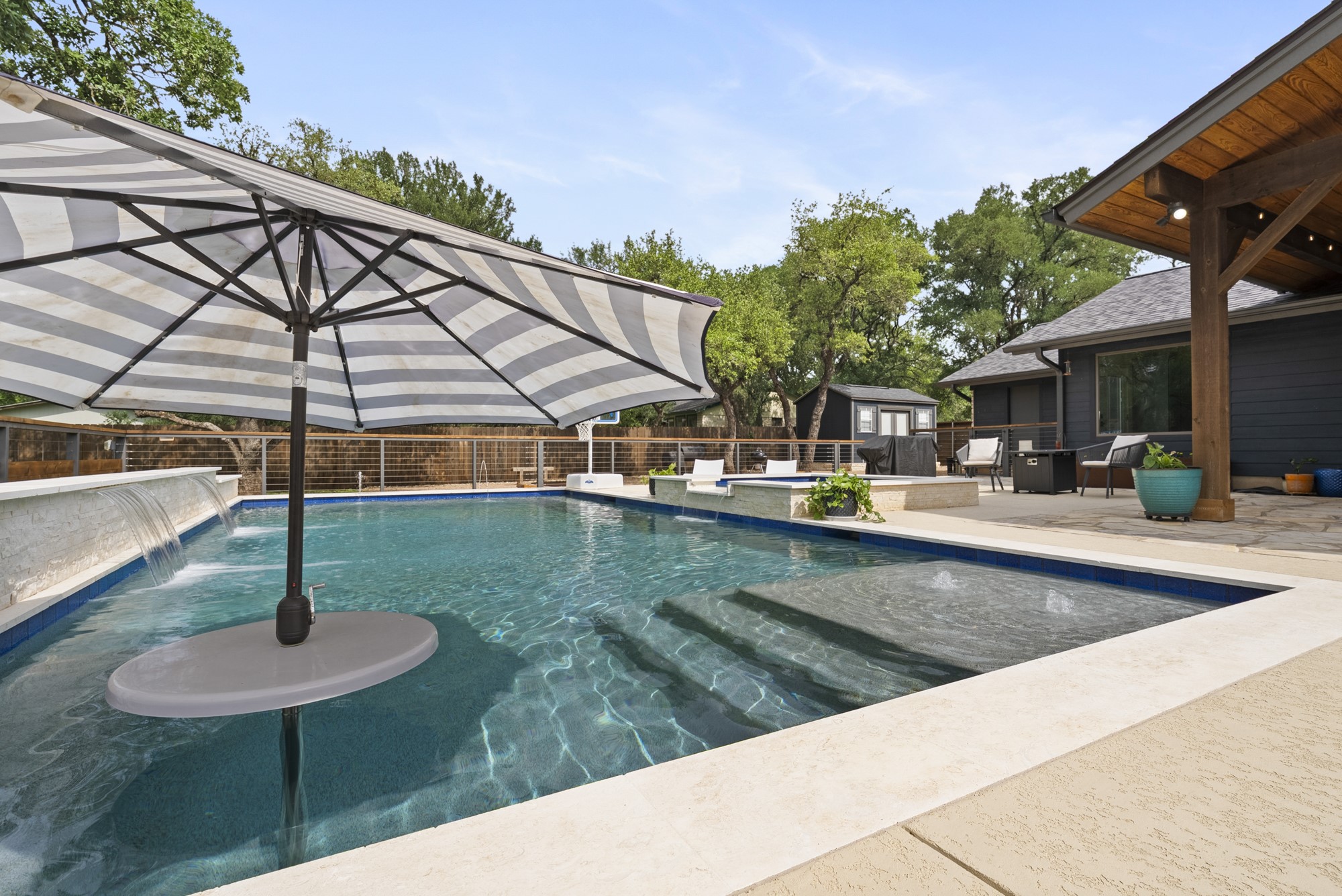 2802 Robin Road Manchaca, TX 78652 - Photo 20 of 40 Sparkling pool featuring a sun shelf with umbrella sleeve, integrated spa, and waterfall feature