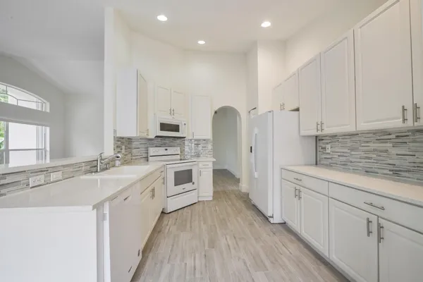a kitchen with white cabinets appliances and sink