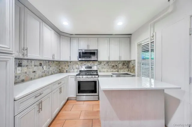 a kitchen with kitchen island granite countertop white cabinets white stainless steel appliances with a sink and dishwasher