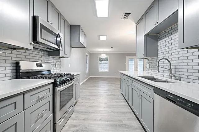 a kitchen with stainless steel appliances granite countertop a sink a stove and a wooden floors