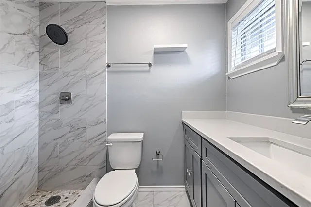 a bathroom with a granite countertop toilet and a sink