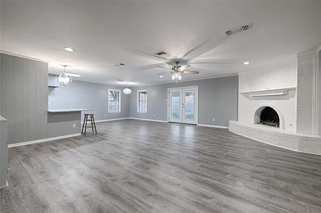a view of an empty room with wooden floor and a fireplace