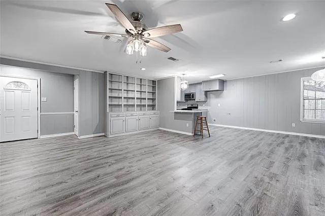 a view of an empty room with a window and wooden floor