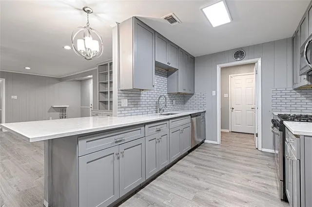 a large kitchen with a sink and dishwasher a kitchen island with wooden floor