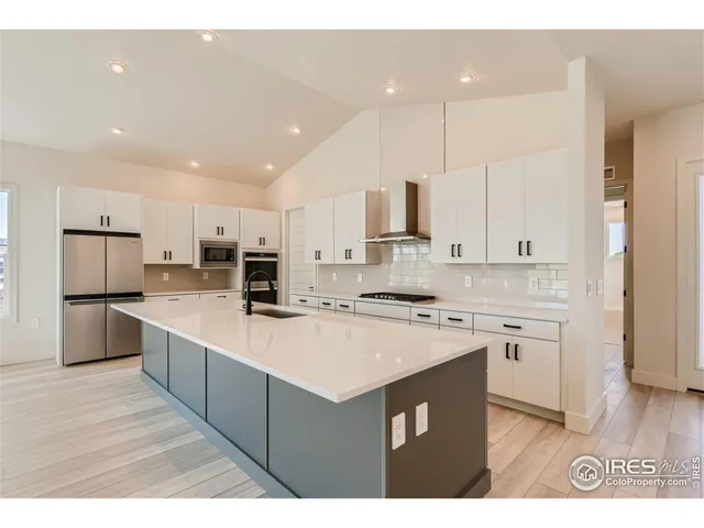 a large kitchen with stainless steel appliances a sink stove and cabinets