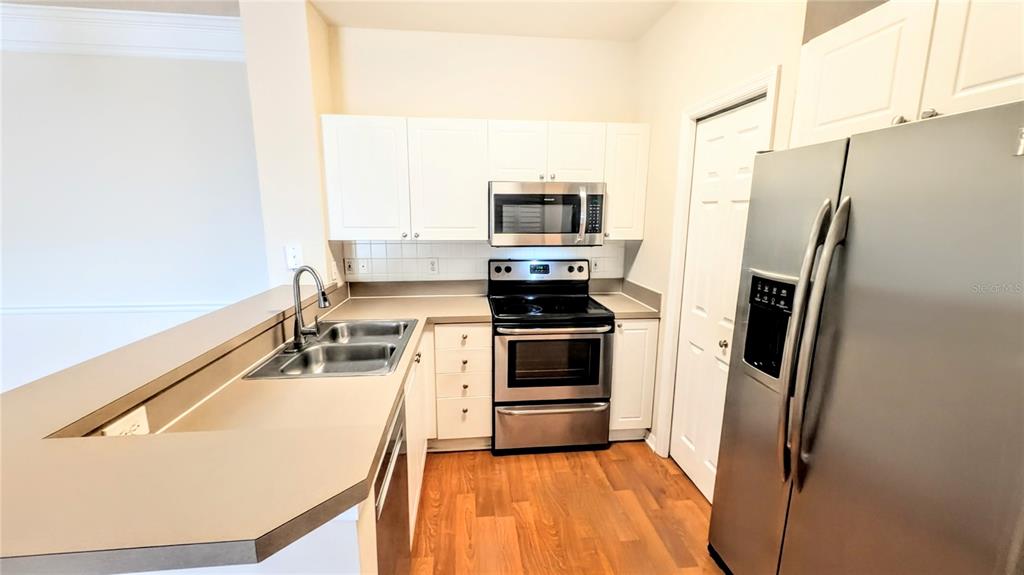5174 Northridge Road, Unit 102 Sarasota, FL 34238 - Photo 8 of 39 a kitchen with white cabinets and stainless steel appliances