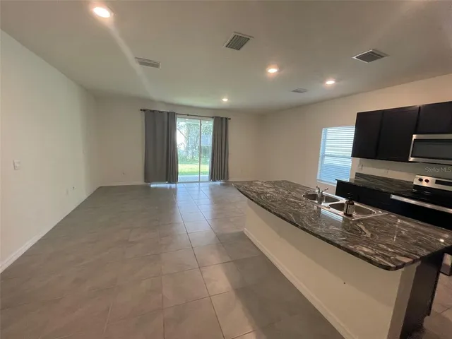 a large kitchen with kitchen island granite countertop a sink and a stove top oven