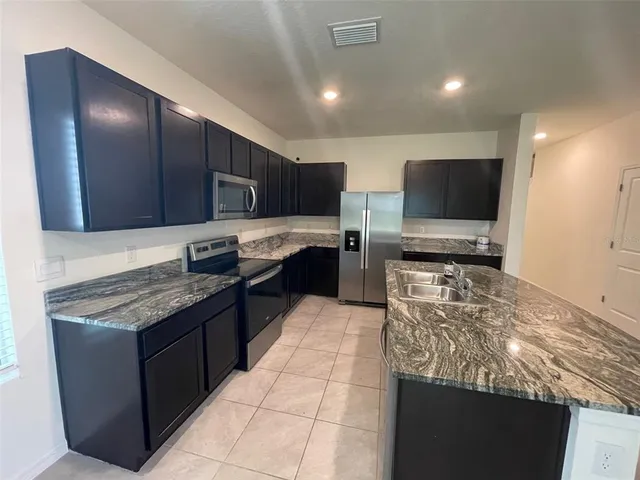 a kitchen with stainless steel appliances granite countertop a stove top oven a sink and a microwave