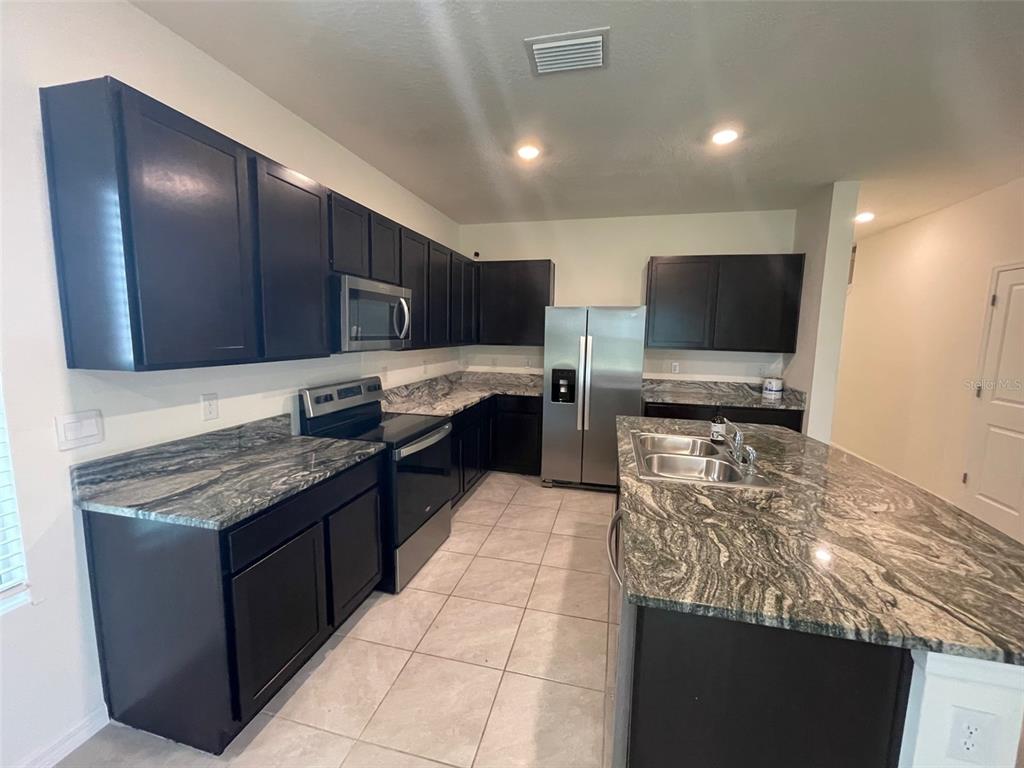 13808 Northwest 9th Road Newberry, FL 32669 - Photo 3 of 24 a kitchen with stainless steel appliances granite countertop a stove top oven a sink and a microwave