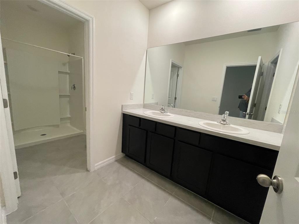 13808 Northwest 9th Road Newberry, FL 32669 - Photo 5 of 24 a bathroom with a double vanity sink a mirror and a bathtub