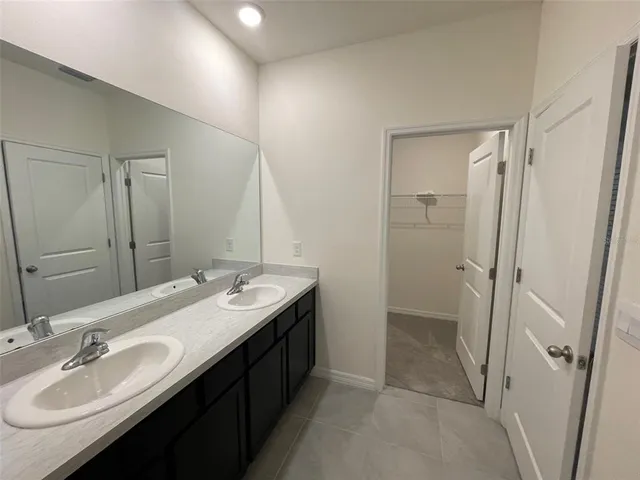 a spacious bathroom with a double vanity sink a mirror and a shower