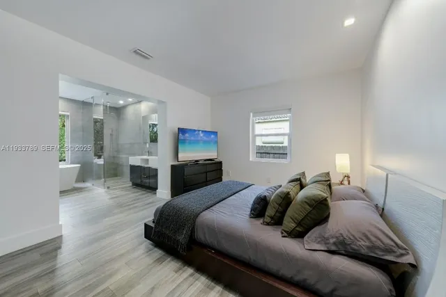 a spacious bedroom with a bed a couch and a view of kitchen