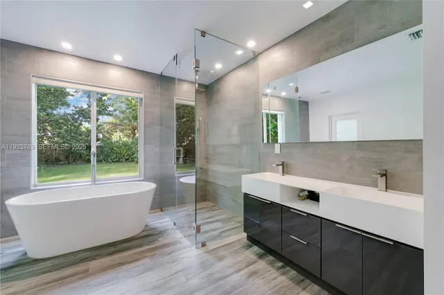 a bathroom with a double vanity sink large mirror and a bathtub