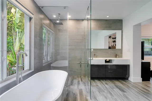 a bathroom with a bathtub a sink and a large window