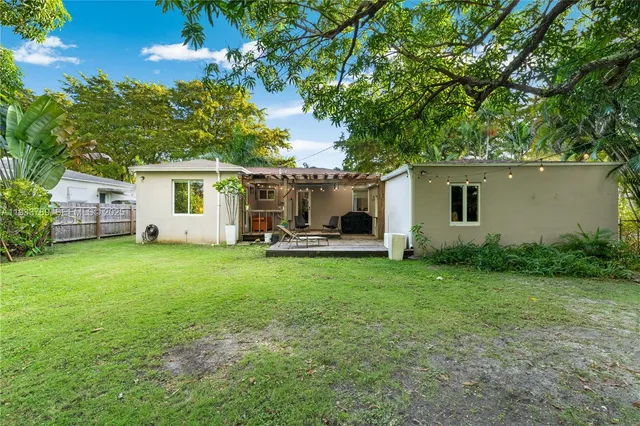 a view of a white house in front of a big yard with large trees