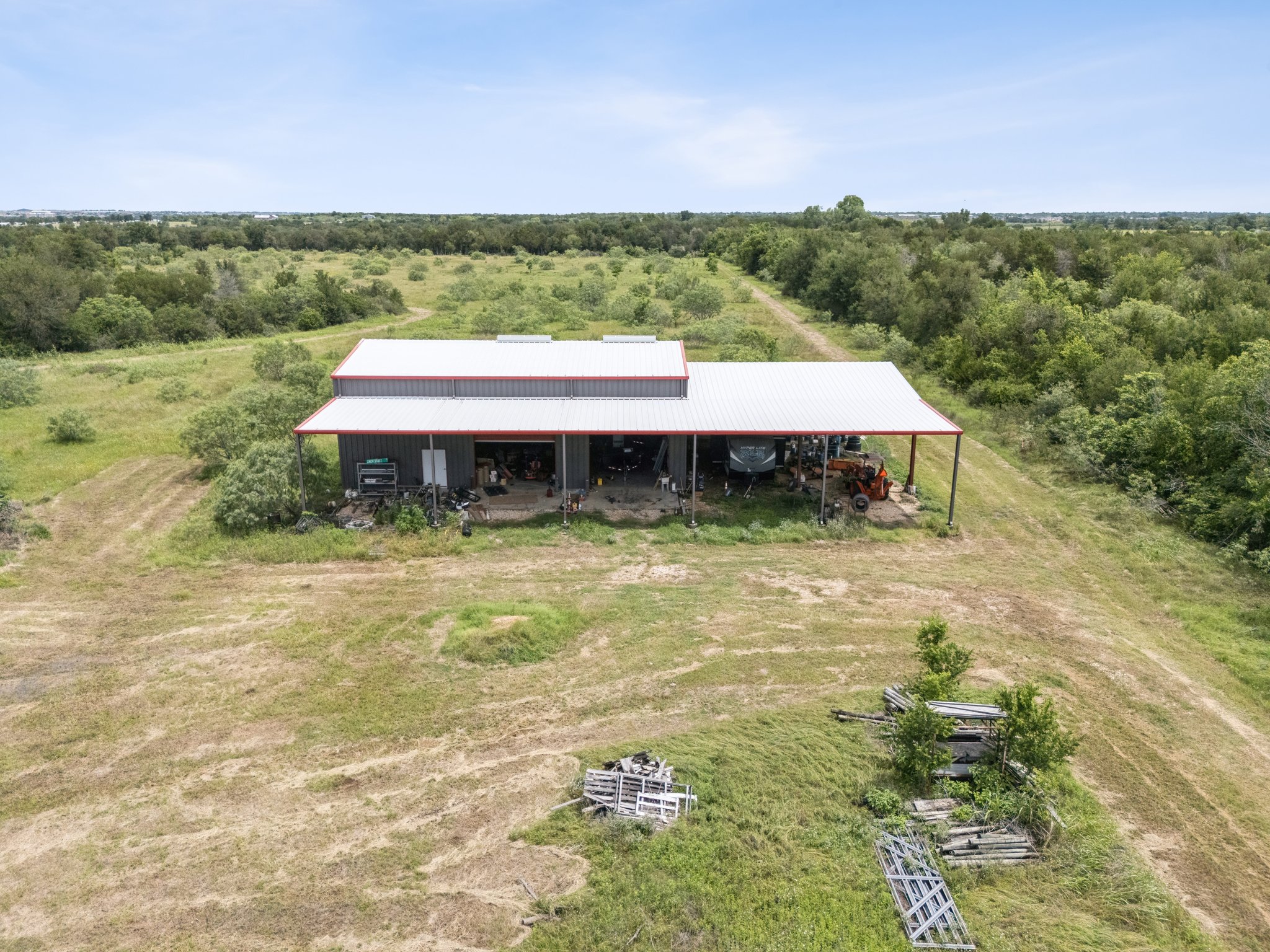 406 Monkey Road Elgin, TX 78621 - Photo 31 of 39 Metal-sided barn structure featuring an extended covered porch area, a pitched metal roof, and an open bay for storage or workspace