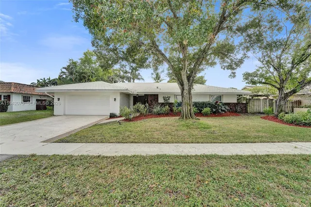 a view of a house with a big yard plants and large trees