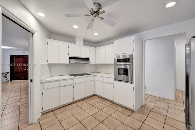 a large white kitchen with a large counter top appliances and cabinets