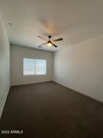 an empty room with a ceiling fan and window
