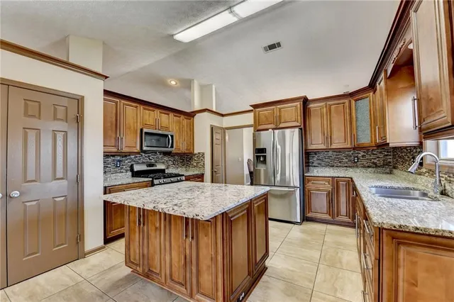 a kitchen with granite countertop a sink stove refrigerator and cabinets