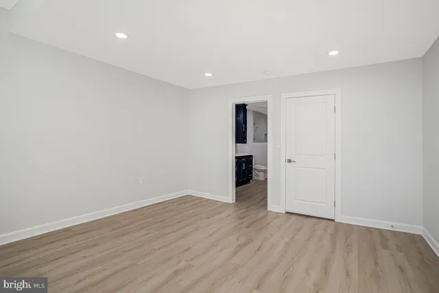 a view of an empty room with wooden floor and closet