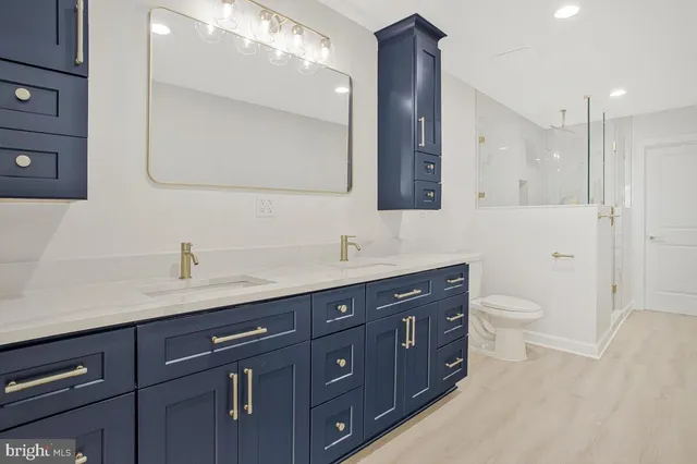 a spacious bathroom with a granite countertop double vanity sink a mirror and a toilet